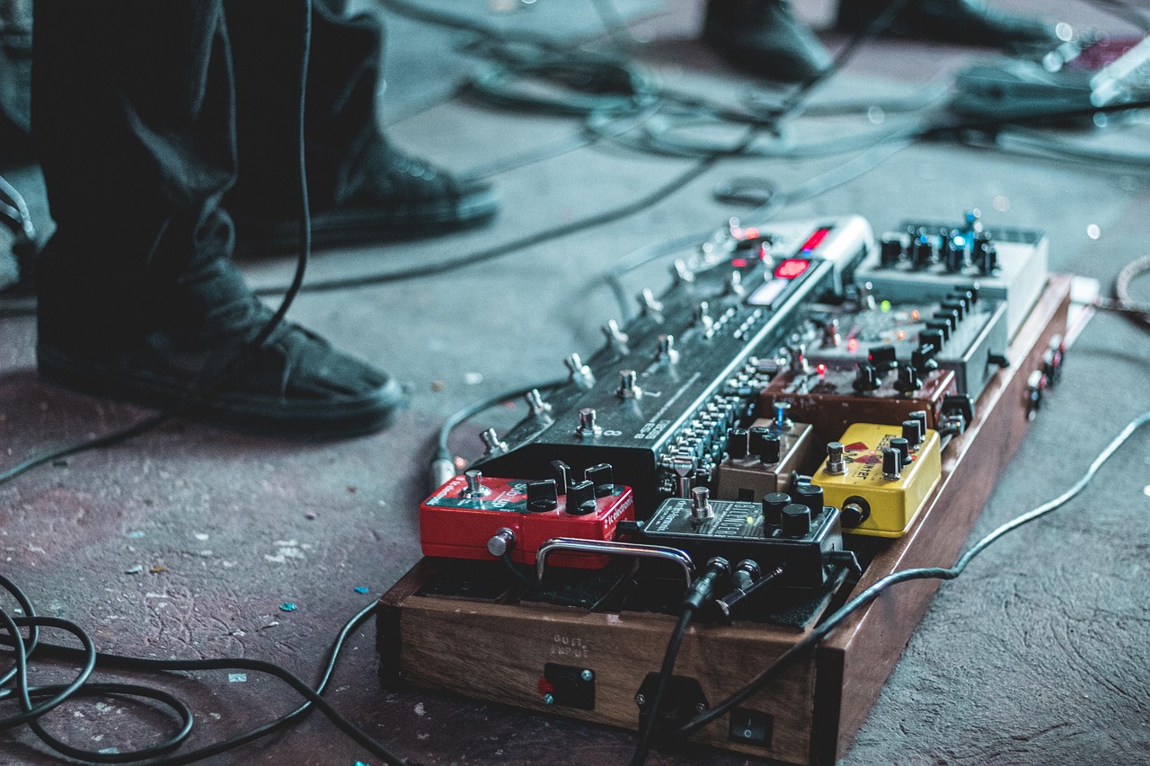 Guitar effects pedalboard on a stage floor with cables